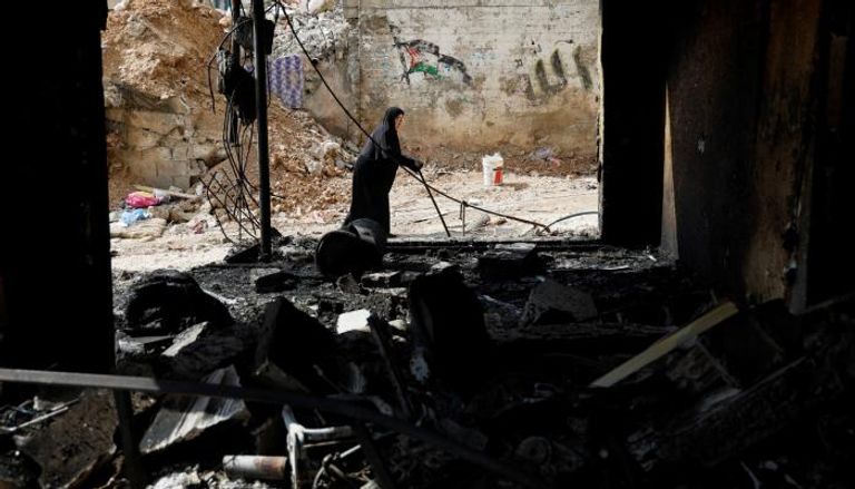 سيدة فلسطينية تمر أمام منزل مدمر جراء الاعتداء الإسرائيلي على نور شمس