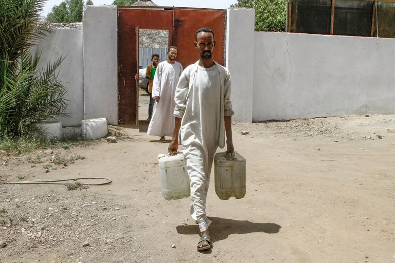سوداني ينقل شوالا من محصول على ظهره - AFP
