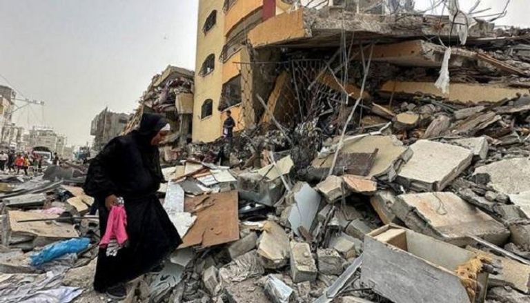 غزاوية أمام مبنى دمره القصف الإسرائيلي