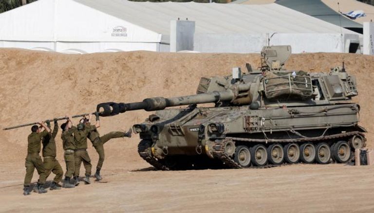 جنود إسرائيليون ينظفون ماسورة وحدة مدفعية متنقلة على الحدود مع غزة