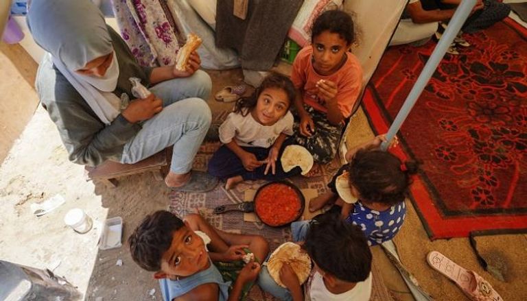 سيدة فلسطينية وأطفالها يتقاسمون وجبة في غزة