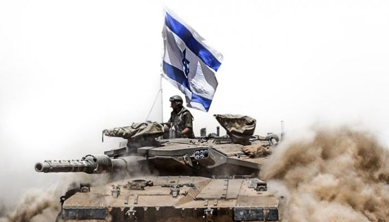 جندي إسرائيلي يقف على دبابة قرب الحدود بين إسرائيل وغزة