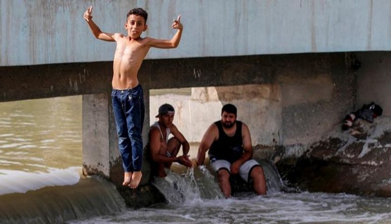 صبية يهربون من الحرارة الشديدة بالسباحة في نهر دجلة