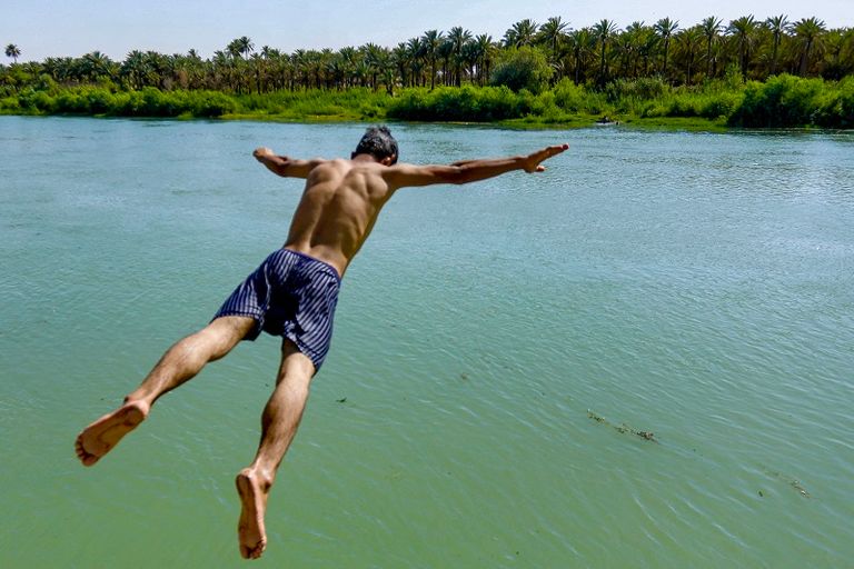 صبية يهربون من الحرارة الشديدة بالسباحة في نهر دجلة