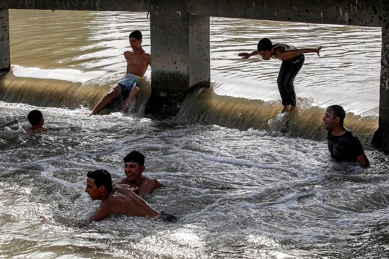 صبية يهربون من الحرارة الشديدة بالسباحة في نهر دجلة