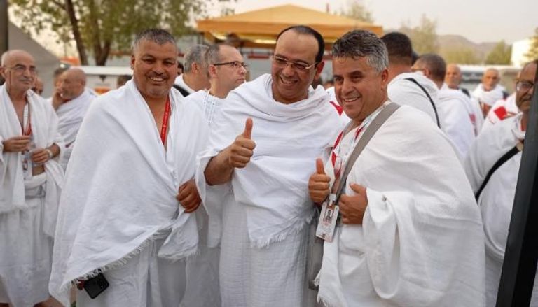 وزير الشؤون الدينية التونسي إبراهيم الشائبي يتوسط حاجين