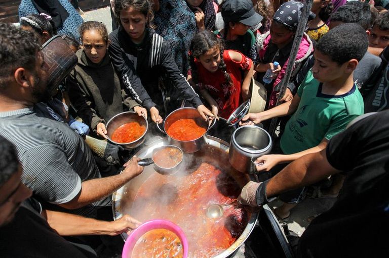 أشخاص يشقون طريقهم عبر أنقاض المباني التي دمرت خلال القصف الإسرائيلي على غزة