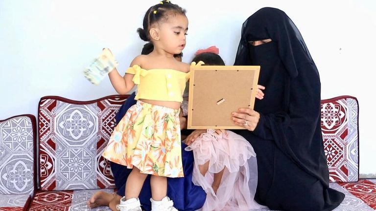 السيدة اليمنية نجلاء وأطفالها يتطلعون لصورة زوجها المختطف