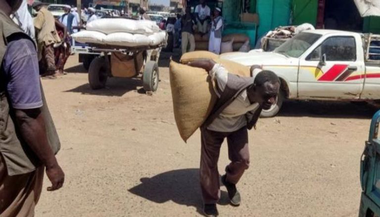 سوداني ينقل شوالا من محصول على ظهره - AFP