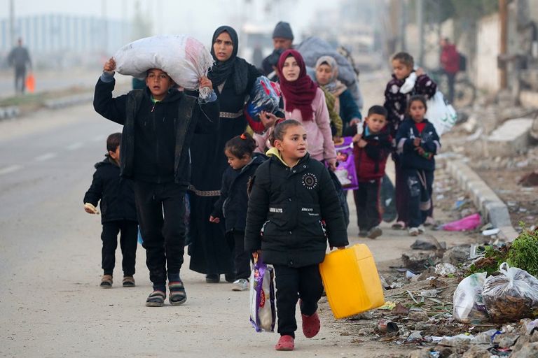 فلسطينية تحتضن طفلها بينما تنتظر السماح بالعودة إلى شمال غزة