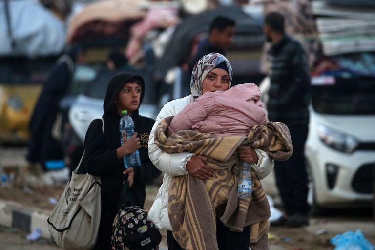 فلسطينية تحتضن طفلها بينما تنتظر السماح بالعودة إلى شمال غزة