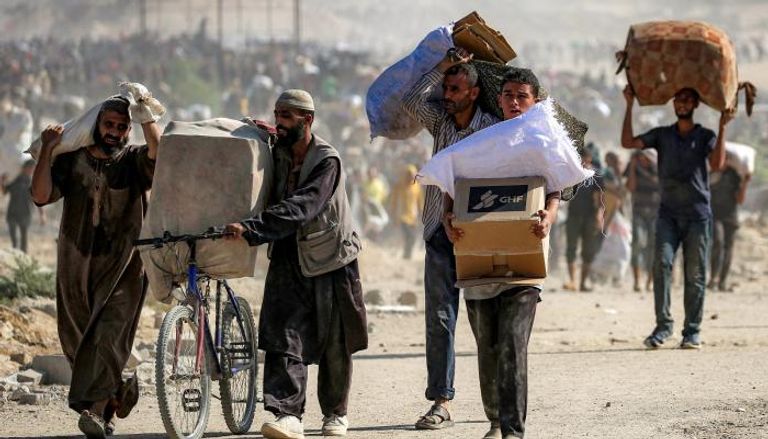 فلسطينيون يحملون أكياسًا من المساعدات الإنسانية قرب ممر نتساريم