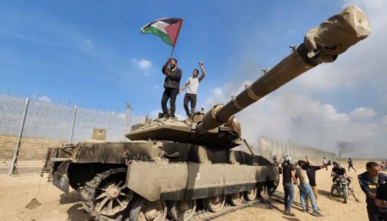 فلسطينيون يرفعون علم فلسطين فوق دبابة إسرائيلية يوم الهجوم