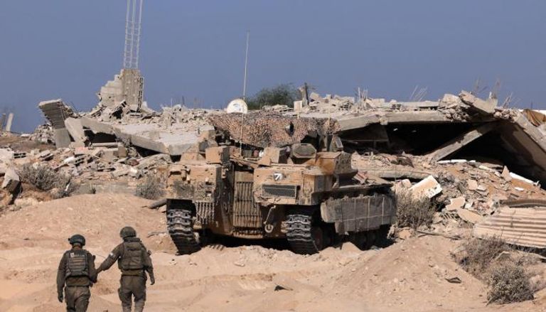 جنديان إسرائيليان يقفان إلى جانب دبابة في غزة
