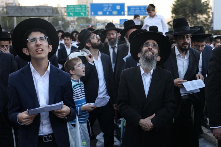 رجال من الحريديم ينظرون إلى الحشود في المظاهرة