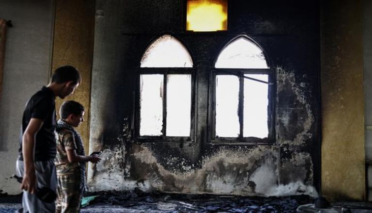 فلسطينيان يتفحصان المسجد المحترق