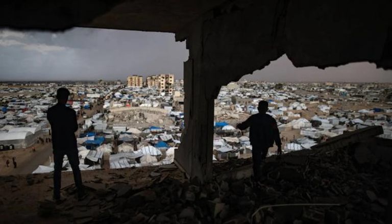 طفلان فلسطينيان في مبنى مهدم يطل على خيام نازحين