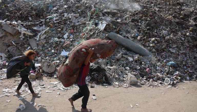 طفلان في غزة يحملان أمتعتهما أمام صاروخ لم ينفجر 