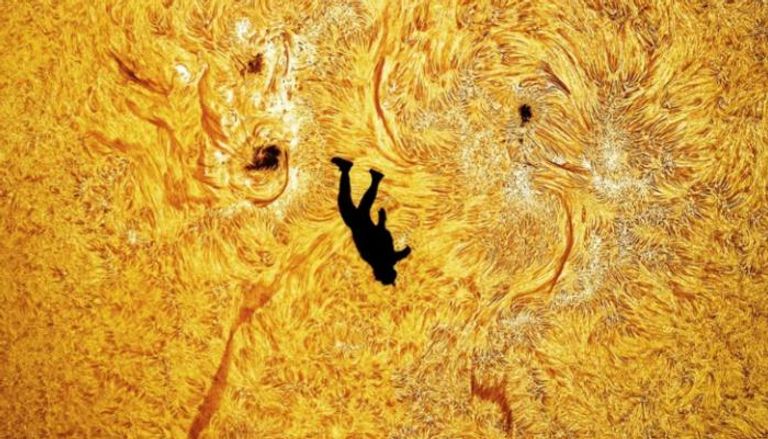 مصور يوثق صورة لمظلي يبدو وكأنه يسقط أمام سطح الشمس