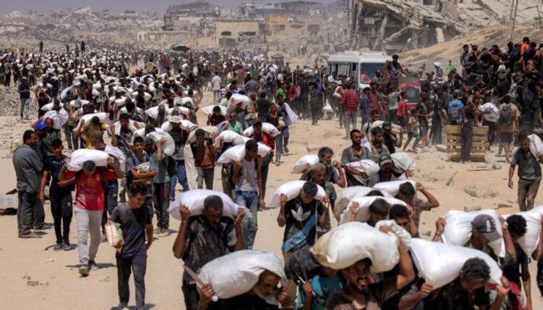 فلسطينيون في غزة يحملون أجولة المساعدات - أرشيفية