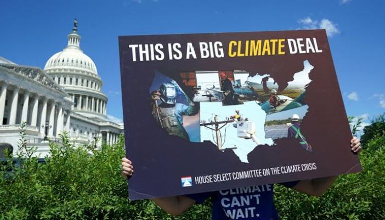 متطوع يحمل لافتة خلال مؤتمر صحفي حول أزمة المناخ في الكابيتول الأمريكي - رويترز