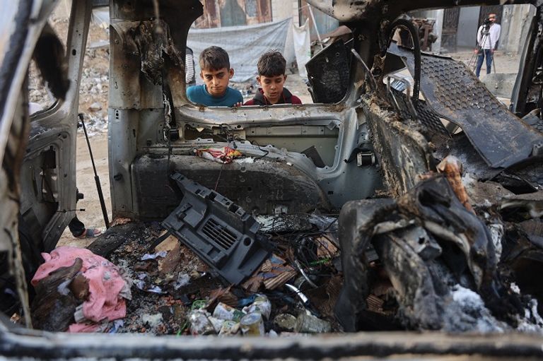 فلسطينيون وسط أنقاض أحد المنازل بغزة - أ.ف.ب