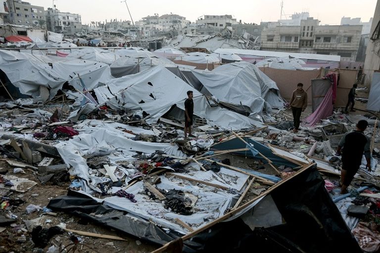 فلسطينيون وسط أنقاض أحد المنازل بغزة - أ.ف.ب