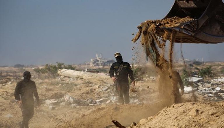 مسلحون ملثمون من حركة الجهاد يبحثون عن جثث في النصيرات بوسط غزة