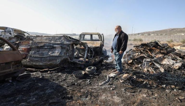 فلسطيني يتفقد سيارات عقب هجوم مستوطنين