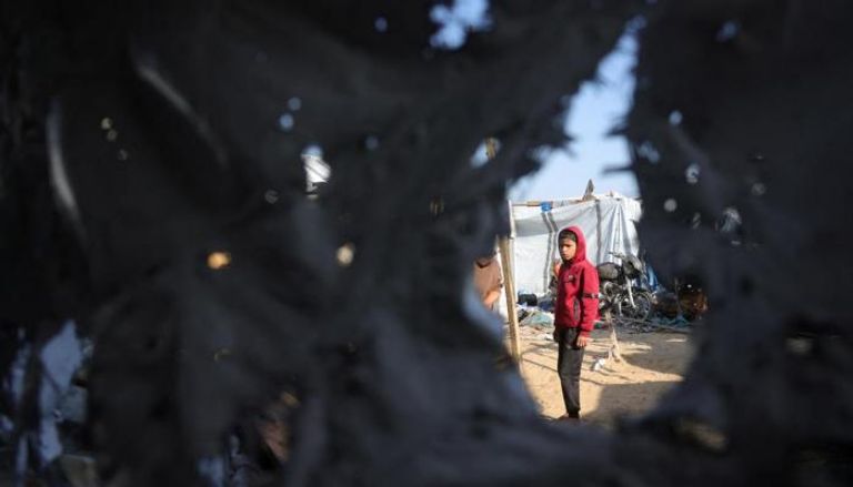 طفل فلسطيني يقف في موقع استهدفته غارة إسرائيلية بغزة