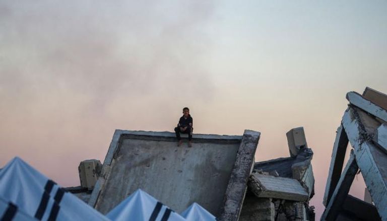 طفل في غزة يجلس على أنقاض منزل دمرته الحرب
