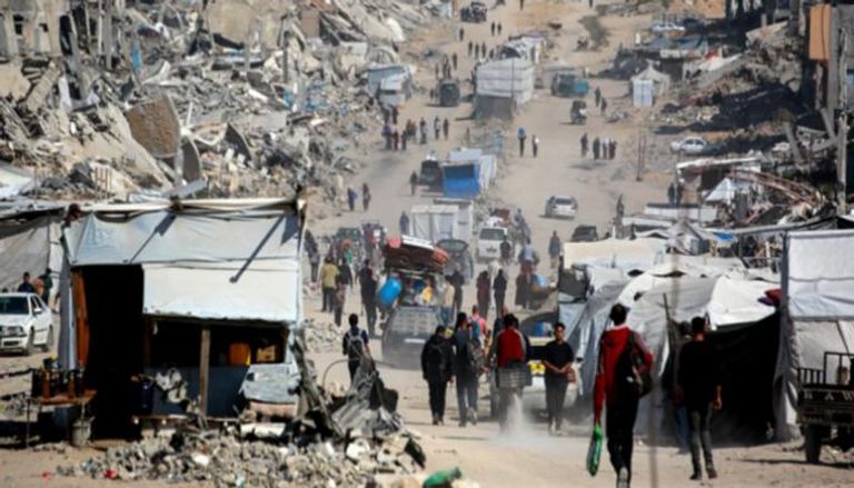 فلسطينيون يسيرون بين الركام في غزة