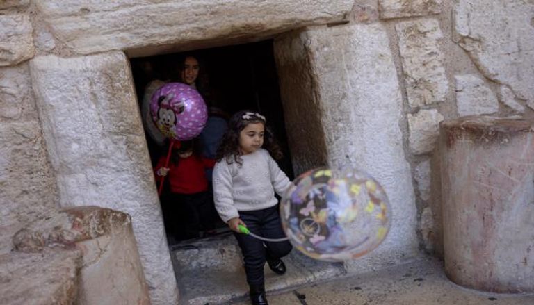 أطفال يحملون بالونات يمرون عبر باب التواضع في كنيسة المهد