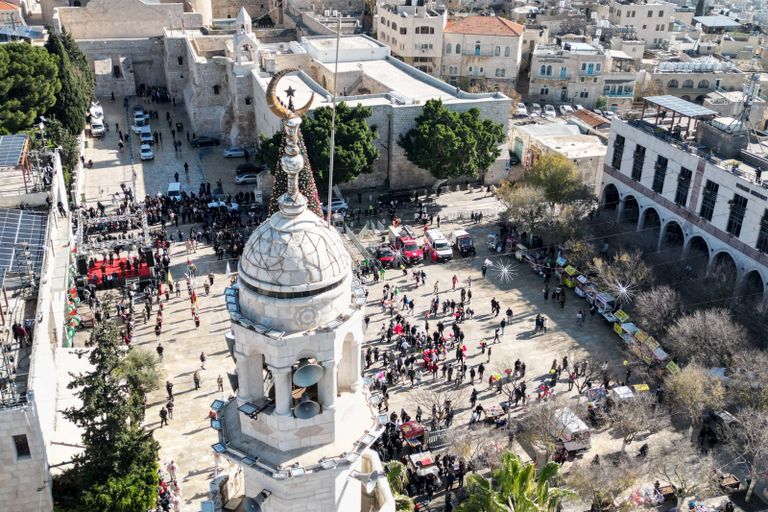 أطفال يحملون بالونات يمرون عبر باب التواضع في كنيسة المهد