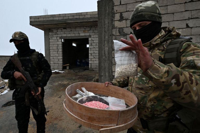 رائد من القوات السورية يشير إلى آلة بمصنع مخدرات معطل في ريف القصير