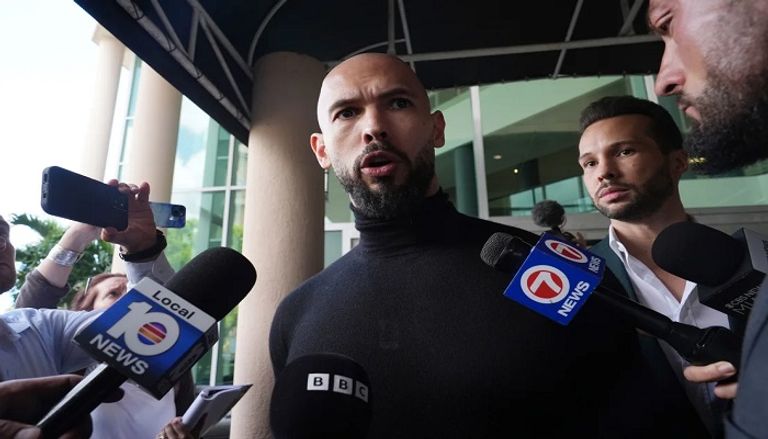 أندرو تيت أنصار كالين جورجيسكو يسيرون أمام لافتة دونالد ترامب