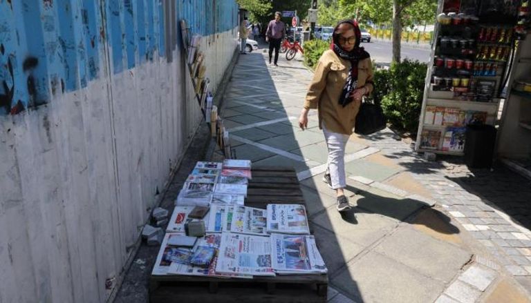 امرأة تمر بجانب كشك لبيع الصحف في طهران