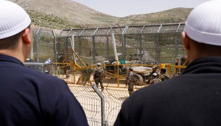 جنود إسرائيليون يحرسون احتجاجا لرجال دروز قرب الحاجز الحدودي في الجولان