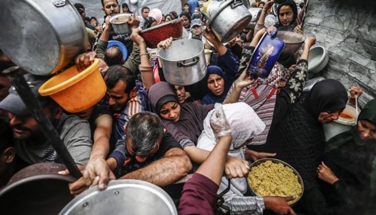 فلسطينيون، معظمهم أطفال، ينتظرون في طوابير طويلة للحصول على مساعدات غذائية