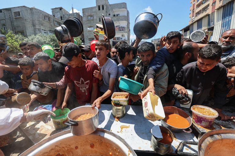 حشد من الفلسطينيين المحاصرين بغزة يتجمعون حول نقطة توزيع وجبات