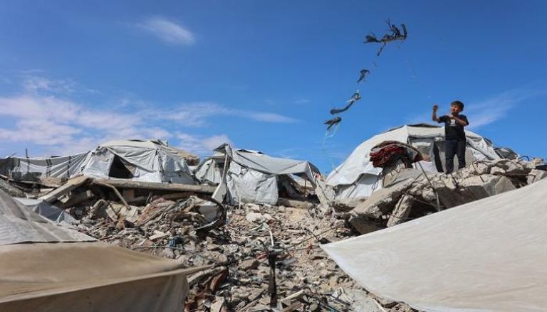 صبي فلسطيني يُحلّق بطائرة ورقية قرب خيام نُصبت على أنقاض مبنى في غزة