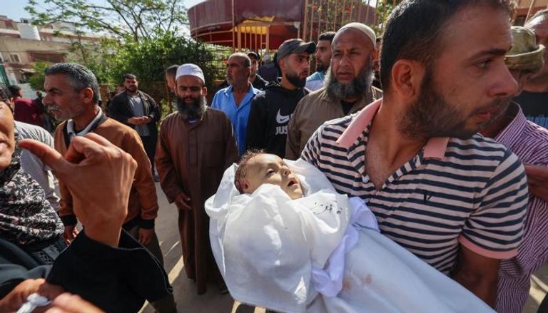 فلسطيني يحمل جثة رضيع في غزة