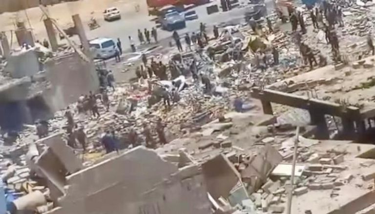 يمنيون على أنقاض مستودع أسلحة حوثي داخل حي مكتظ بالسكان