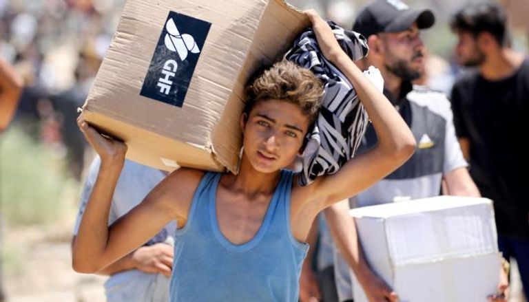 فتى يحمل كرتونة مساعدات في غزة