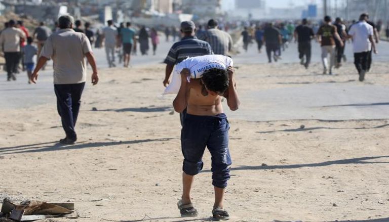 صبي فلسطيني يحمل جوالا من الدقيق