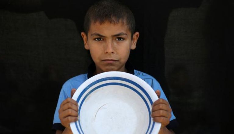 صبي فلسطيني يحمل طبقا فارغا في النصيرات
