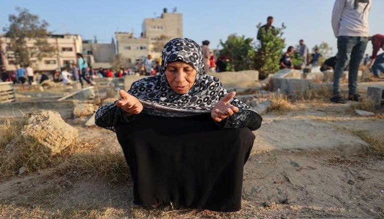 فلسطينية تصلي عند قبر أحد أحبائها في أول أيام عيد الأضحى في النصيرات وسط غزة