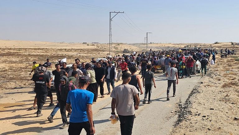 نازحون فلسطينيون يسيرون على طريق لتسلم مساعدات إنسانية من مؤسسة تدعمها أمريكا 