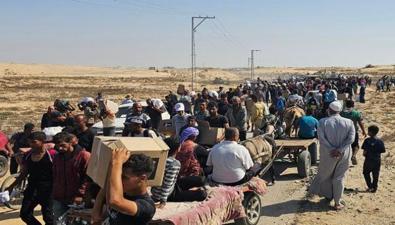 نازحون فلسطينيون يسيرون على طريق لاستلام مساعدات إنسانية من مؤسسة تدعمها أمريكا 