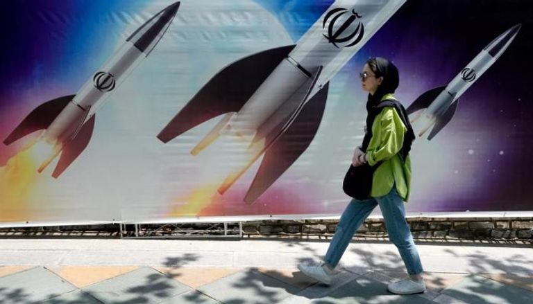 فتاة إيرانية تسير أمام جدارية في طهران- أرشيفية